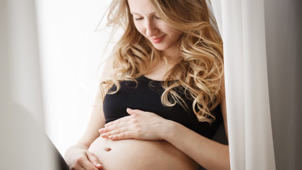 Una donna incinta guarda il suo pancione.