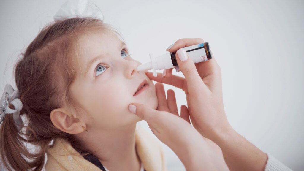 apnee notturne nei bambini, bimba con spray nasale