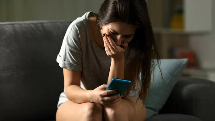 ragazza triste che guarda lo smartphone