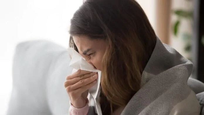 donna ha febbre e raffreddore e si soffia il naso di profilo per la flurona